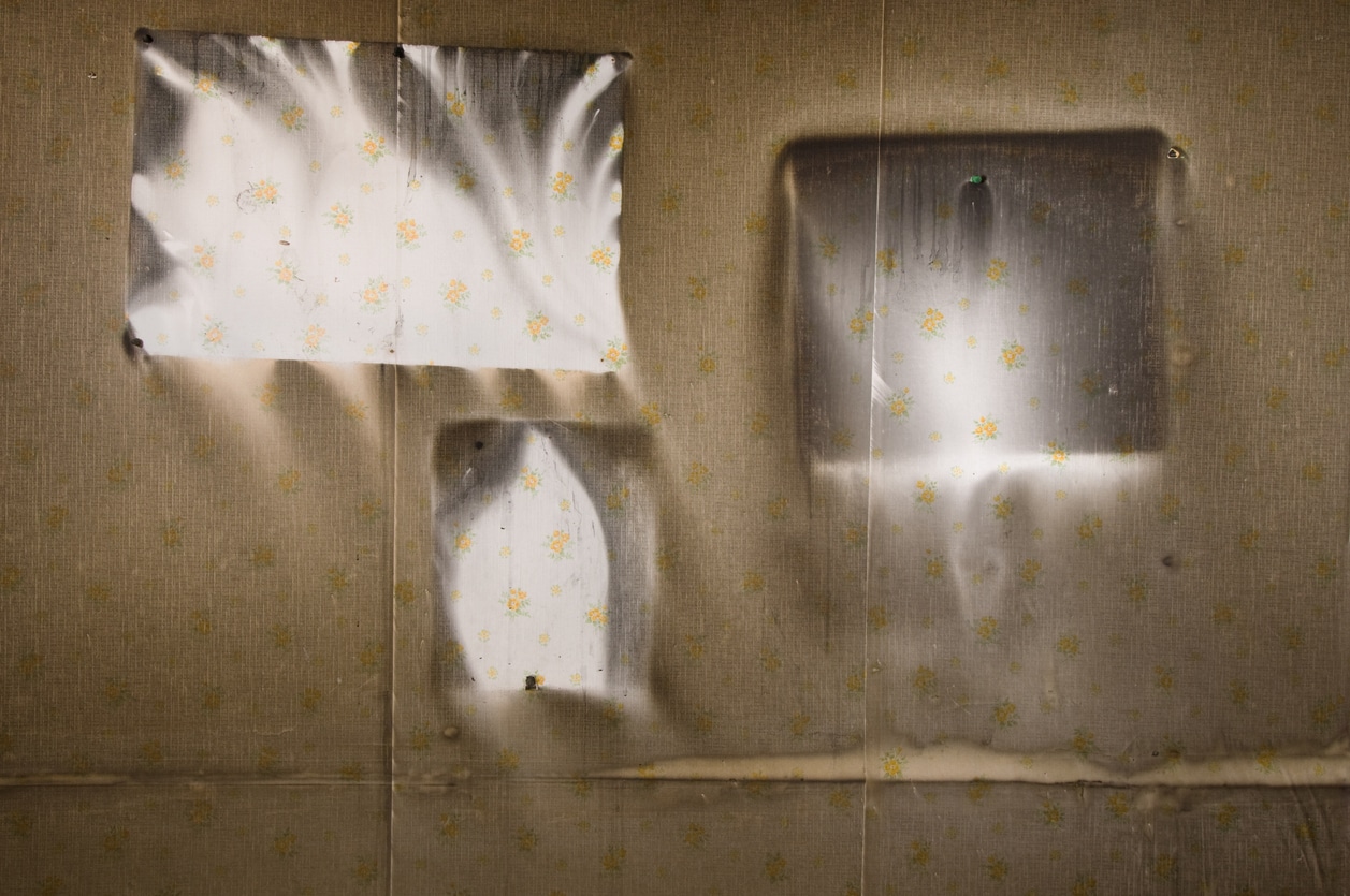 An image of a wall severely damaged by smoke from a fire, shapes on the wall indicate where pictures once hung.