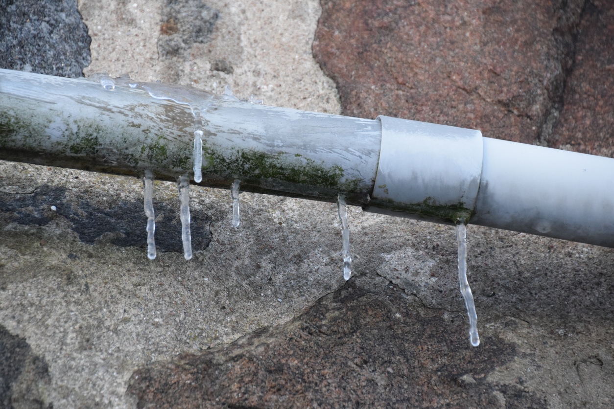 A frozen pipe on the brick wall of a business showing the need for plumbing winterization in Alabama.